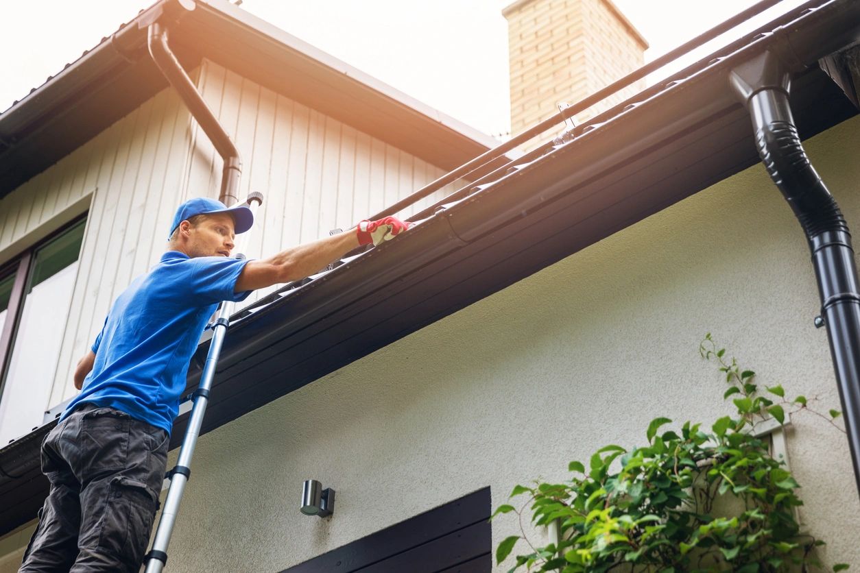 Homeowner cleaning the gutters of his home. Spring cleaning his home roof.